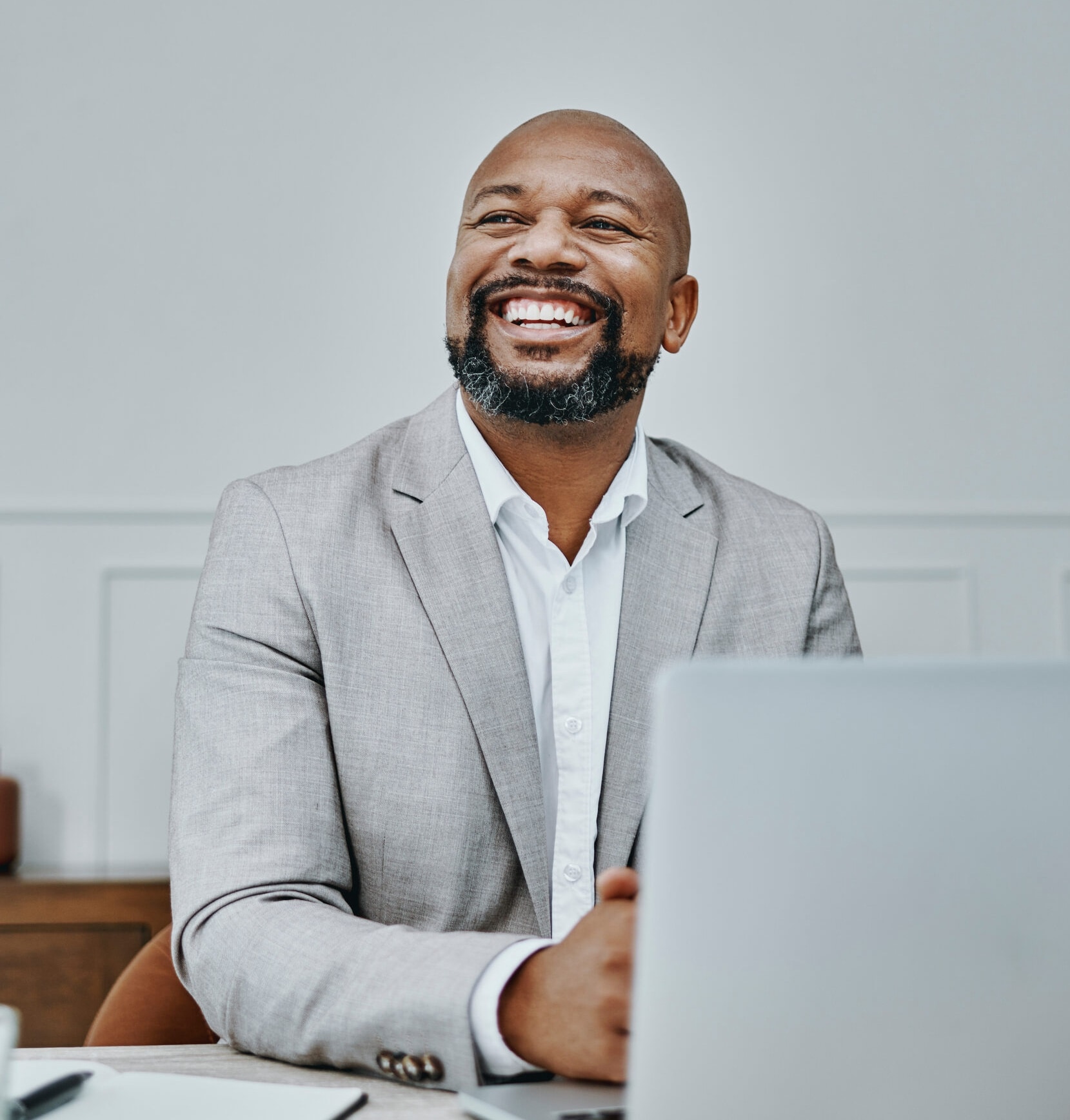 Homme souriant assis à un bureau, devant un ordinateur portable