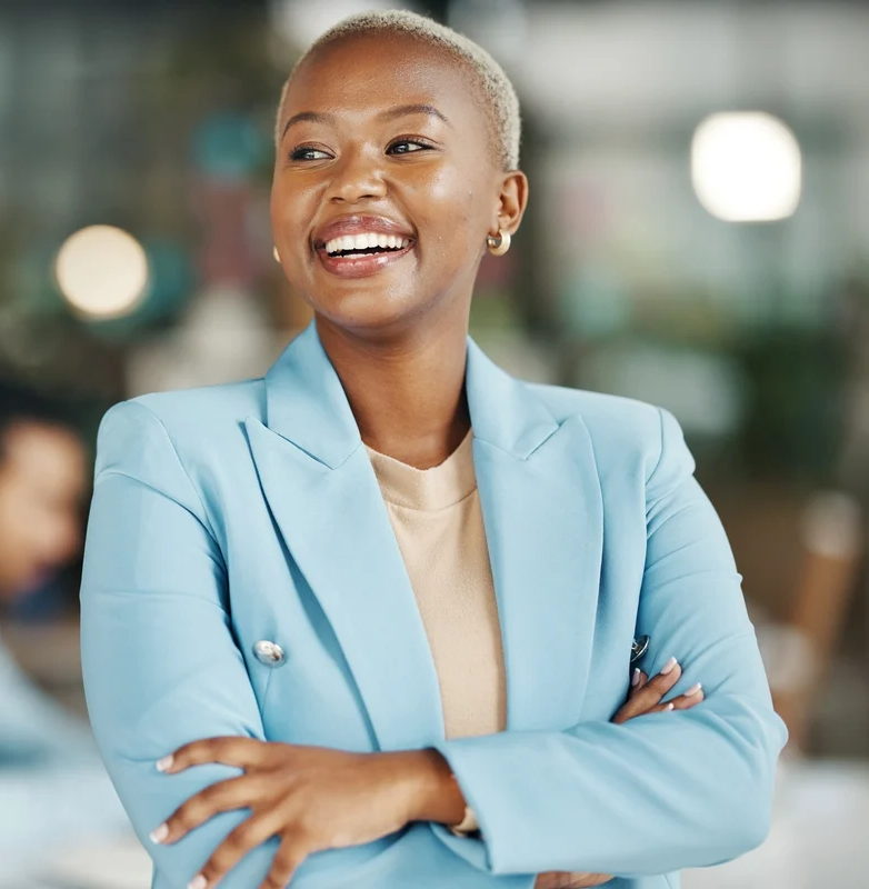 Femme souriante en veste bleue, les bras croisés, dans un bureau